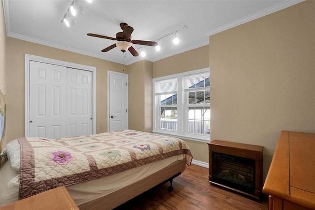 bedroom with ceiling fan, crown molding, dark wood-type flooring, and track lighting