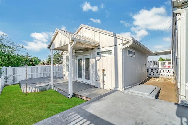 rear view of house featuring a lawn, a patio area, french doors, and a wooden deck