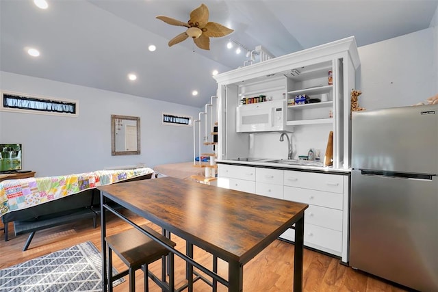 kitchen with vaulted ceiling, ceiling fan, white cabinetry, light hardwood / wood-style floors, and stainless steel refrigerator