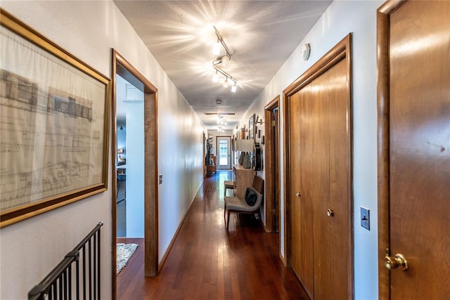 hallway featuring rail lighting and dark hardwood / wood-style floors