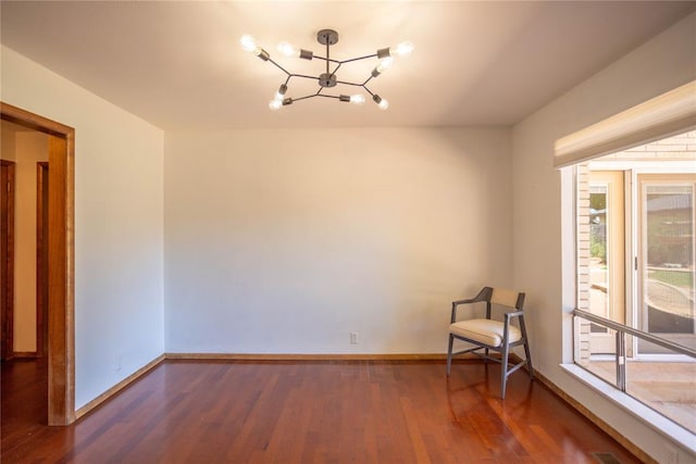 spare room with dark wood-type flooring and a chandelier