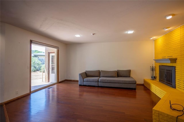 living room featuring dark hardwood / wood-style flooring and a brick fireplace