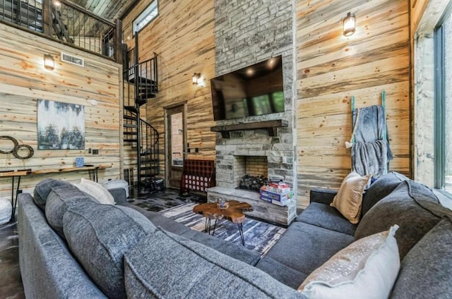 living room featuring a fireplace, high vaulted ceiling, and wood walls