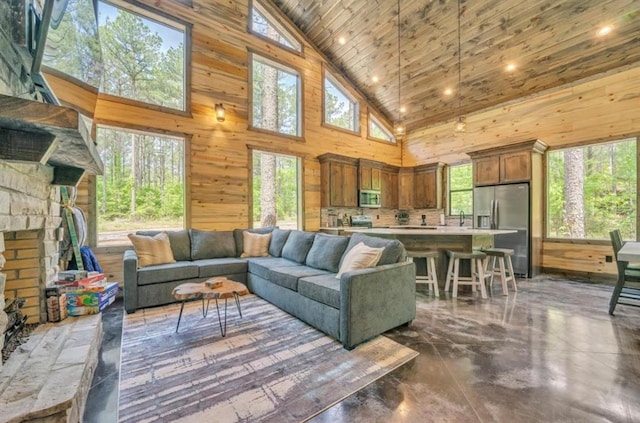 living room with a fireplace, high vaulted ceiling, wooden walls, and sink