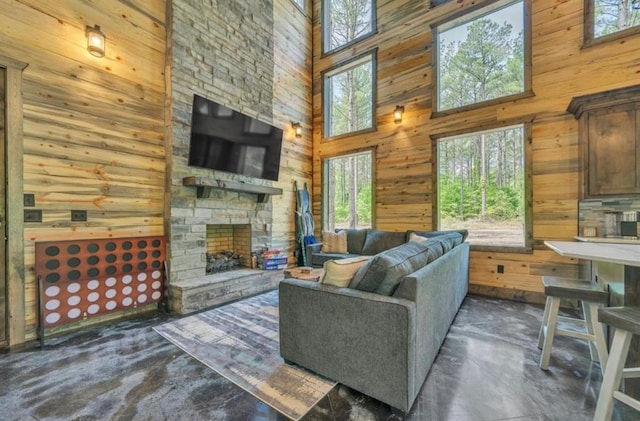 living room with a fireplace, a high ceiling, and wooden walls