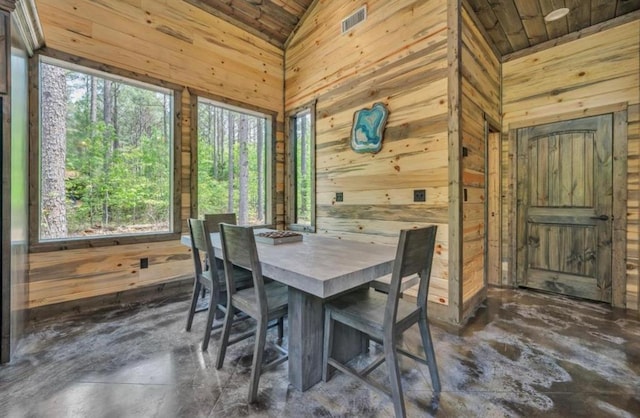 dining room with a wealth of natural light, wooden walls, and wood ceiling