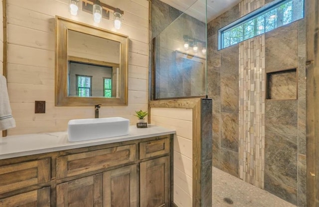 bathroom with vanity, wood walls, and tiled shower