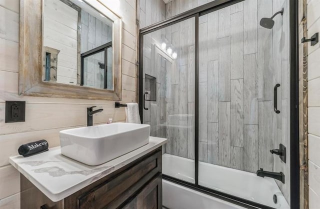 bathroom featuring vanity, enclosed tub / shower combo, and tile walls