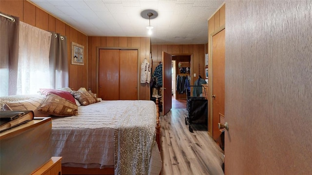 bedroom featuring light hardwood / wood-style floors, a closet, and wood walls