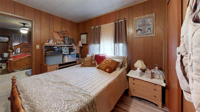 bedroom with wood walls and light wood-type flooring