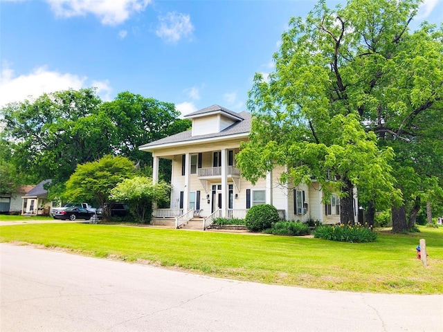 greek revival inspired property featuring a front lawn and a balcony