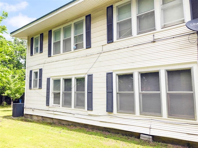 view of side of property with cooling unit and a lawn