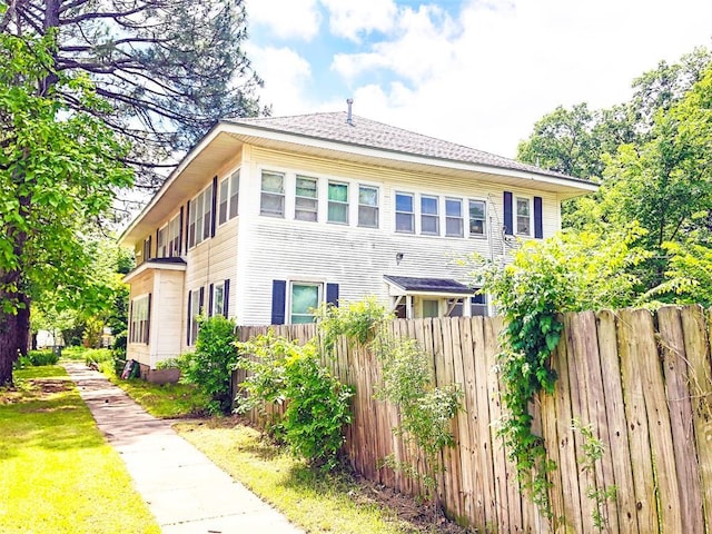 view of home's exterior with a shingled roof and fence