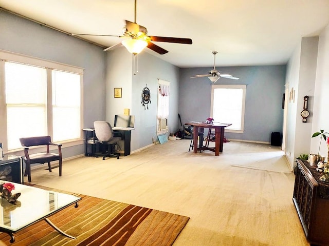 living area featuring light carpet, ceiling fan, and baseboards
