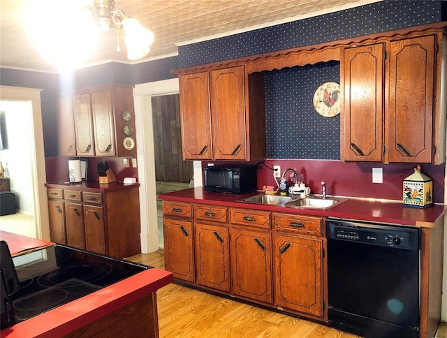 kitchen with light wood-style floors, wallpapered walls, black appliances, a sink, and brown cabinets