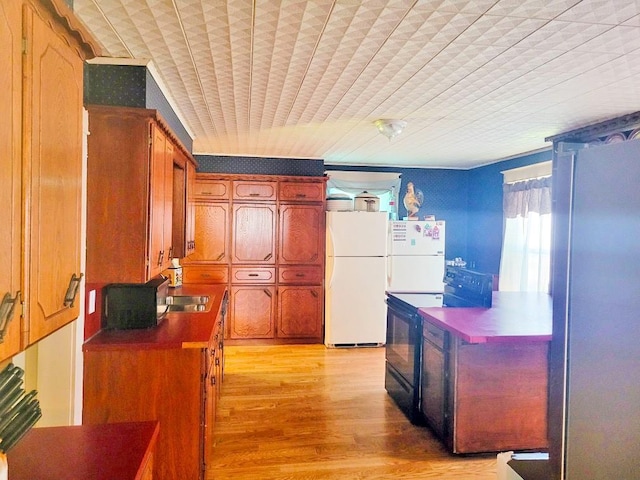 kitchen with dark countertops, black range with electric cooktop, freestanding refrigerator, and light wood-style flooring