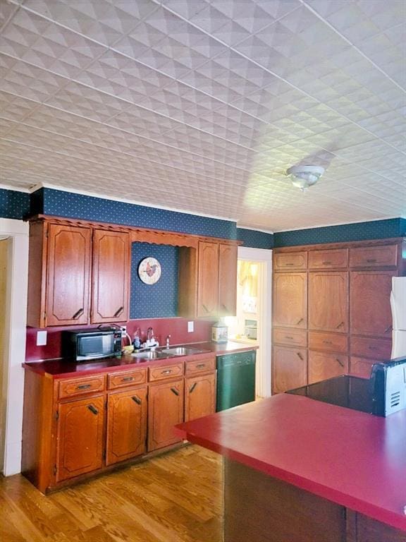 kitchen with a sink, brown cabinetry, light wood-style flooring, and dishwasher