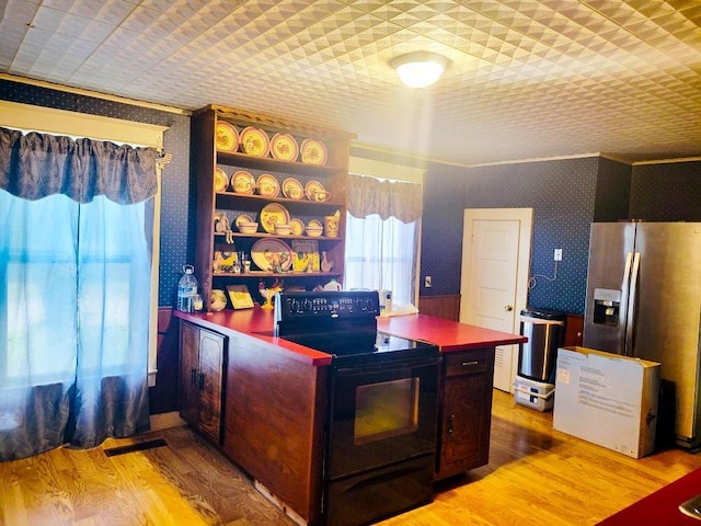 interior space featuring wallpapered walls, light wood-style flooring, dark countertops, stainless steel refrigerator with ice dispenser, and black range with electric cooktop