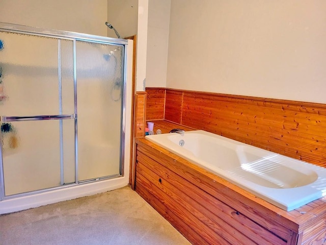 bathroom with wooden walls, a bath, a stall shower, and wainscoting