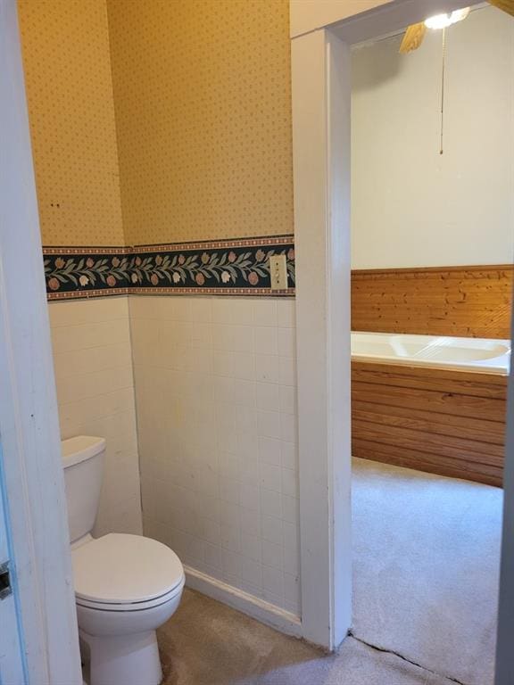bathroom with wainscoting, a ceiling fan, wallpapered walls, and toilet
