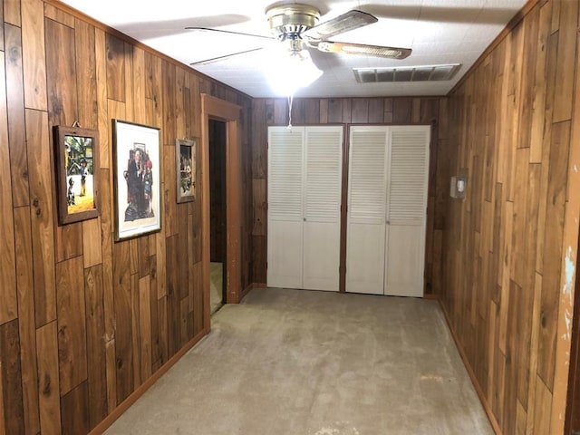hall with wooden walls, visible vents, and light carpet