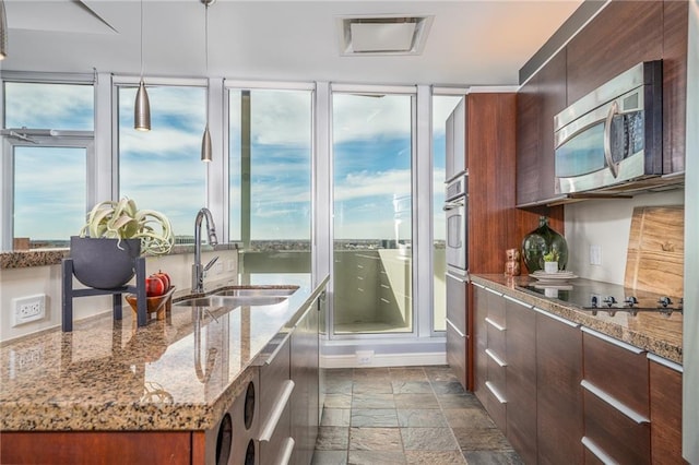 kitchen featuring a kitchen island with sink, sink, light stone countertops, appliances with stainless steel finishes, and washer / dryer