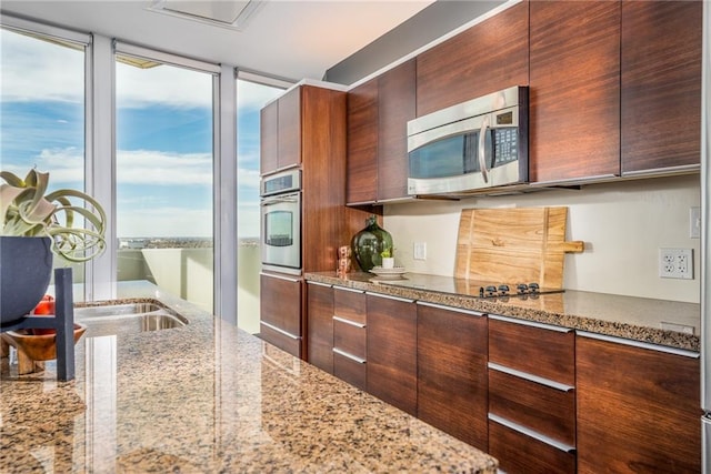 kitchen featuring stainless steel appliances, light stone counters, and a wealth of natural light