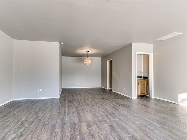 spare room featuring wood-type flooring and an inviting chandelier