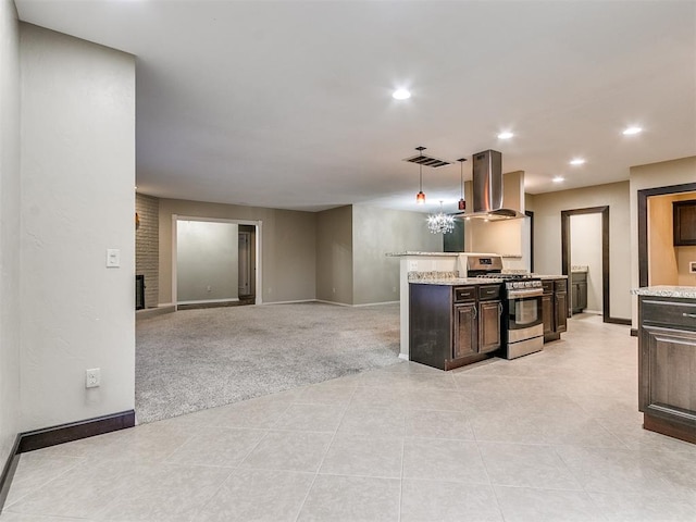 kitchen with pendant lighting, stainless steel gas range, island range hood, light colored carpet, and dark brown cabinetry