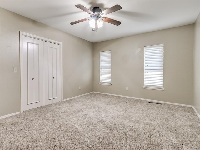 unfurnished bedroom featuring carpet, ceiling fan, and a closet