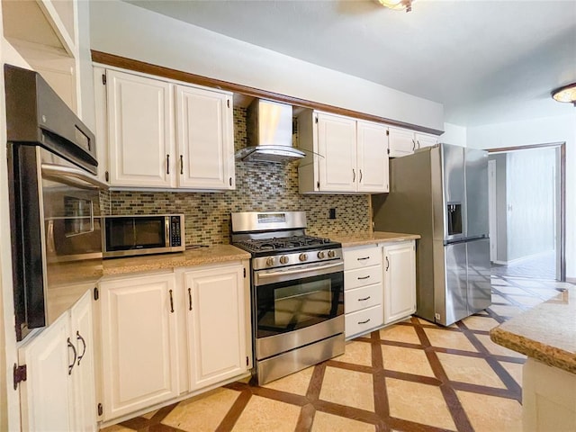 kitchen with backsplash, wall chimney exhaust hood, appliances with stainless steel finishes, light stone counters, and white cabinetry