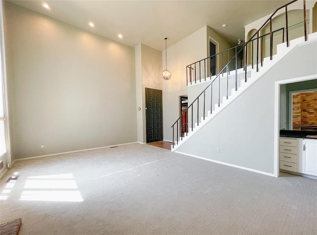 interior space with light colored carpet, a towering ceiling, and an inviting chandelier