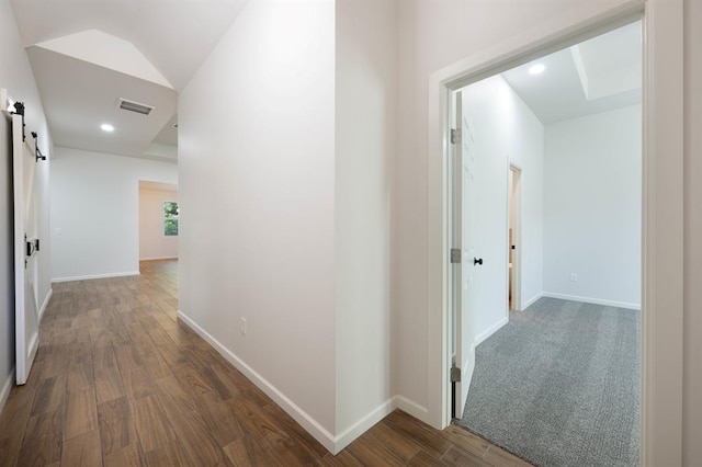 hall featuring dark hardwood / wood-style floors, a barn door, and lofted ceiling