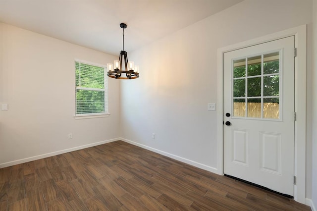 unfurnished dining area featuring a healthy amount of sunlight, dark wood-type flooring, and a chandelier