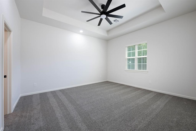 empty room with carpet floors and a tray ceiling