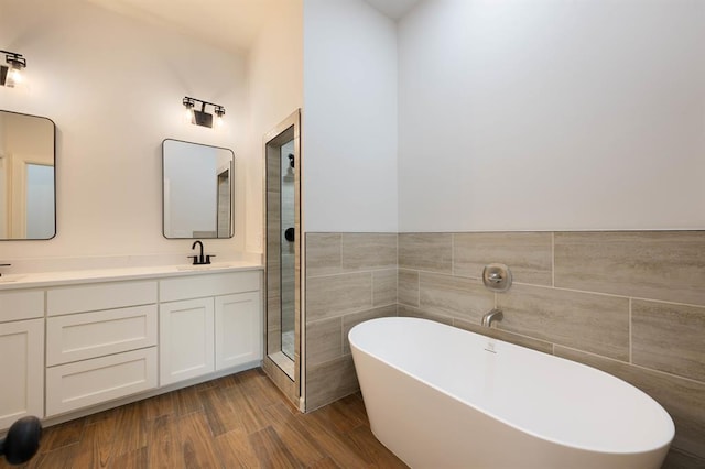 bathroom with separate shower and tub, hardwood / wood-style floors, vanity, and tile walls