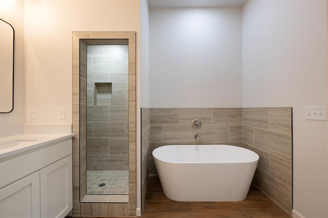 bathroom with hardwood / wood-style flooring, vanity, separate shower and tub, and tile walls