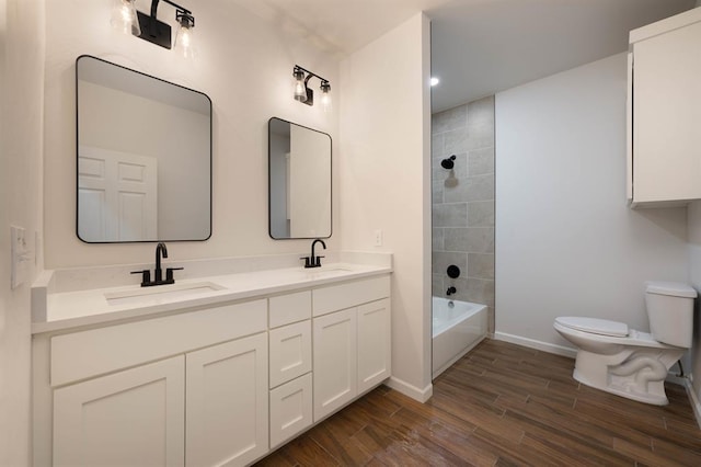 full bathroom featuring vanity, wood-type flooring, tiled shower / bath combo, and toilet