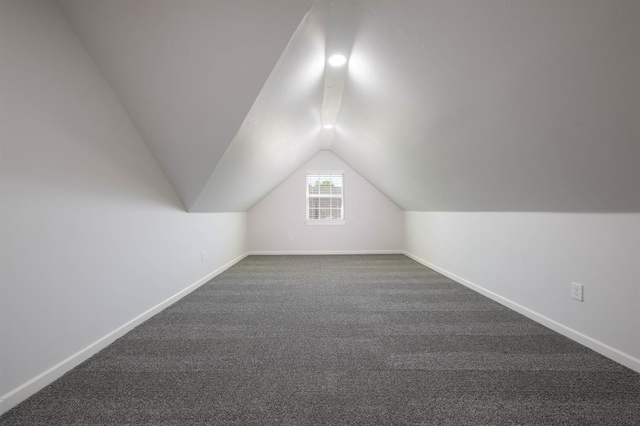 additional living space featuring vaulted ceiling and dark colored carpet