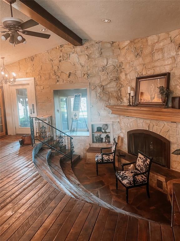 sitting room featuring a stone fireplace, a wealth of natural light, wood-type flooring, and vaulted ceiling with beams