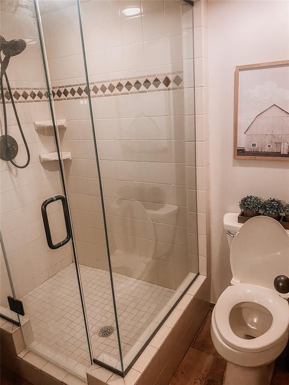 bathroom with tile patterned flooring, toilet, and a shower with shower door