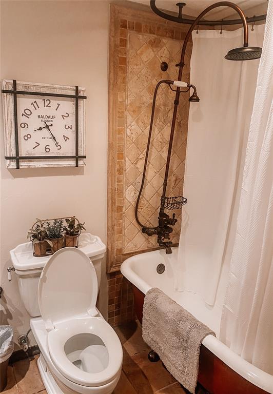 bathroom with tile patterned floors, shower / bath combo with shower curtain, and toilet