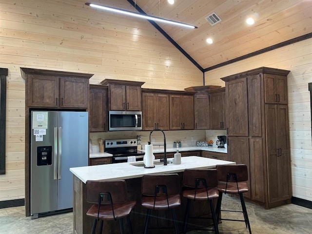 kitchen featuring a center island with sink, dark brown cabinetry, and appliances with stainless steel finishes