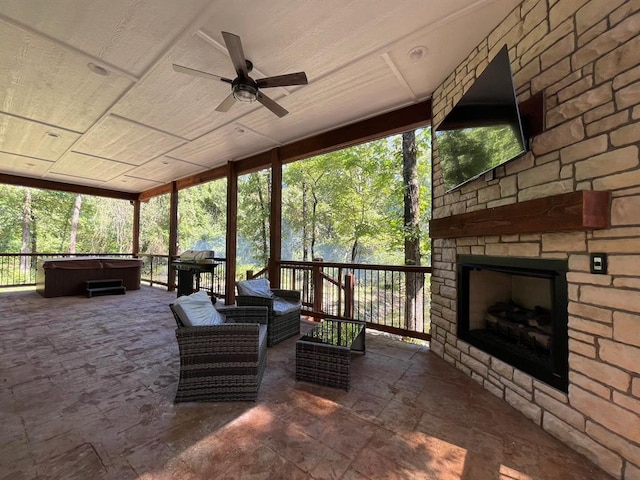 sunroom featuring an outdoor stone fireplace and ceiling fan