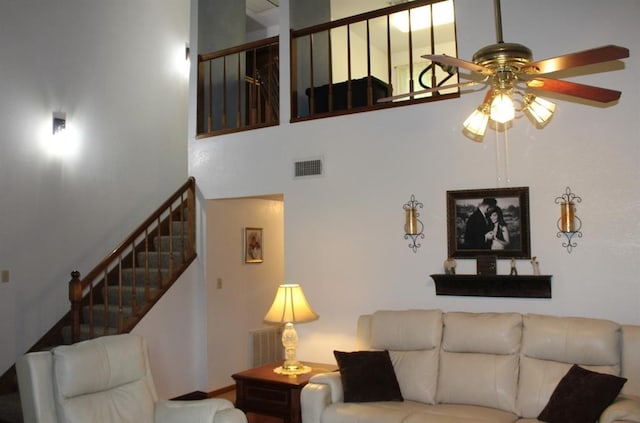 living room with ceiling fan and a high ceiling