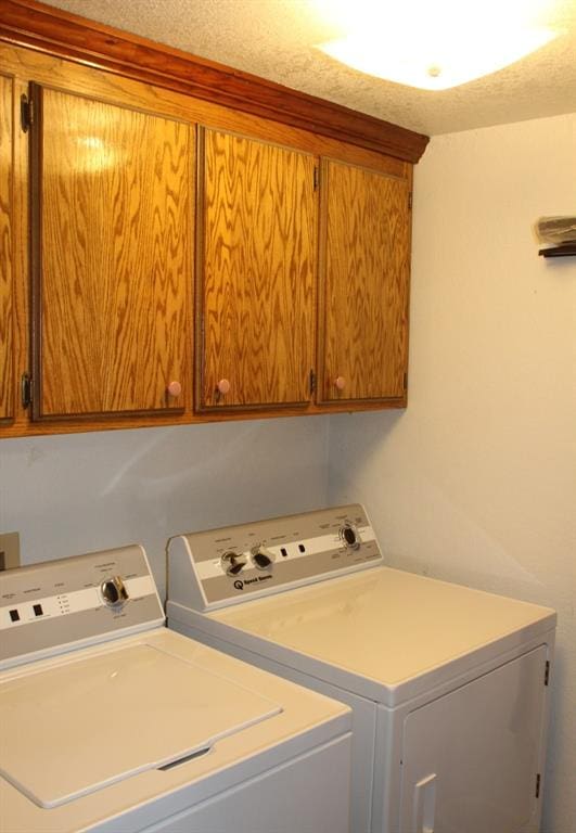 washroom featuring cabinets, a textured ceiling, and independent washer and dryer