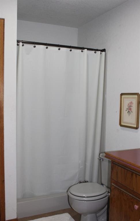 bathroom with vanity, curtained shower, toilet, and a textured ceiling