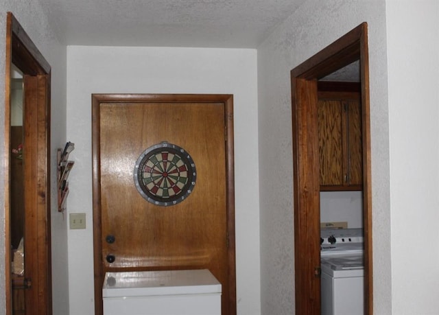 corridor with washer / dryer and a textured ceiling