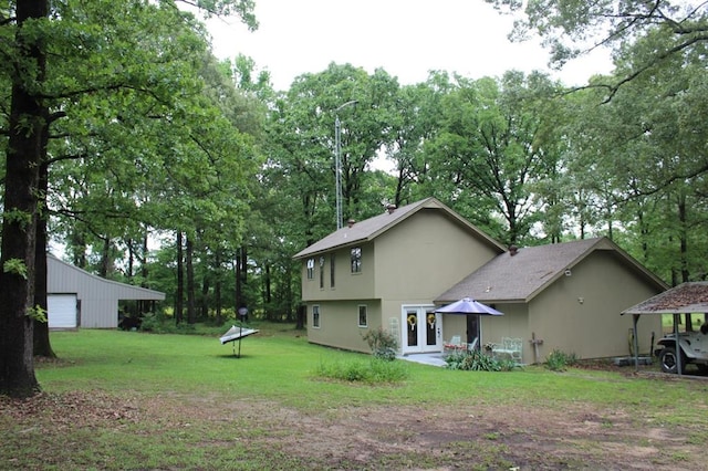 back of property featuring a yard, french doors, and an outbuilding