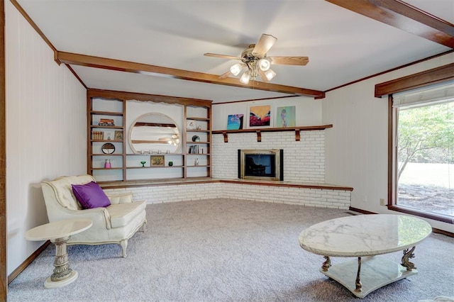 carpeted living room featuring beamed ceiling, crown molding, ceiling fan, and a fireplace